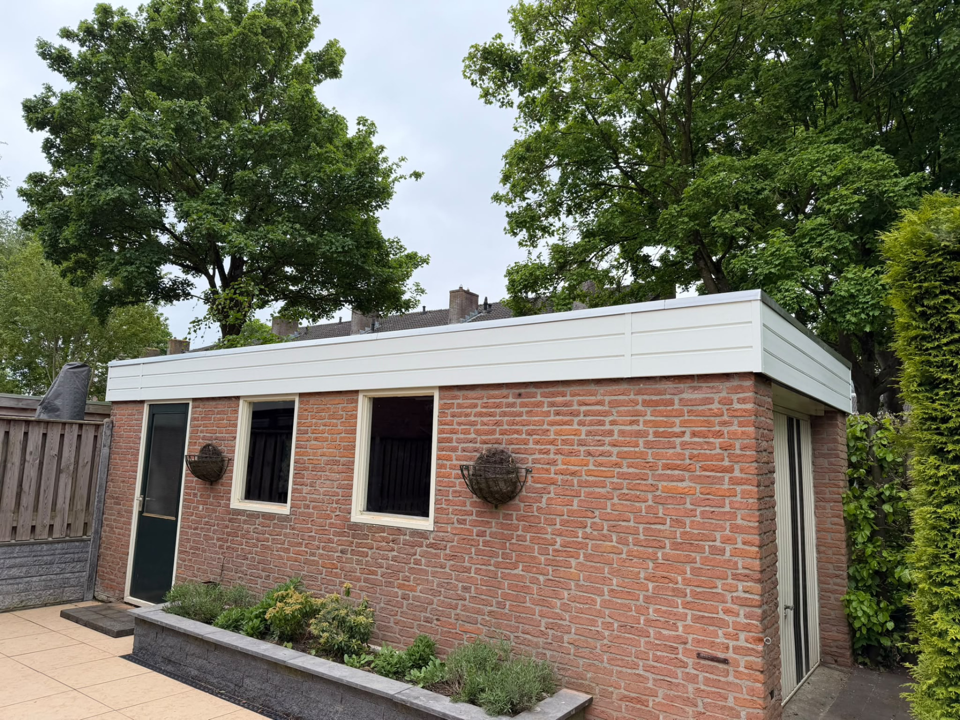 Stenen bijgebouw met nieuw afgewerkte witte dakrand