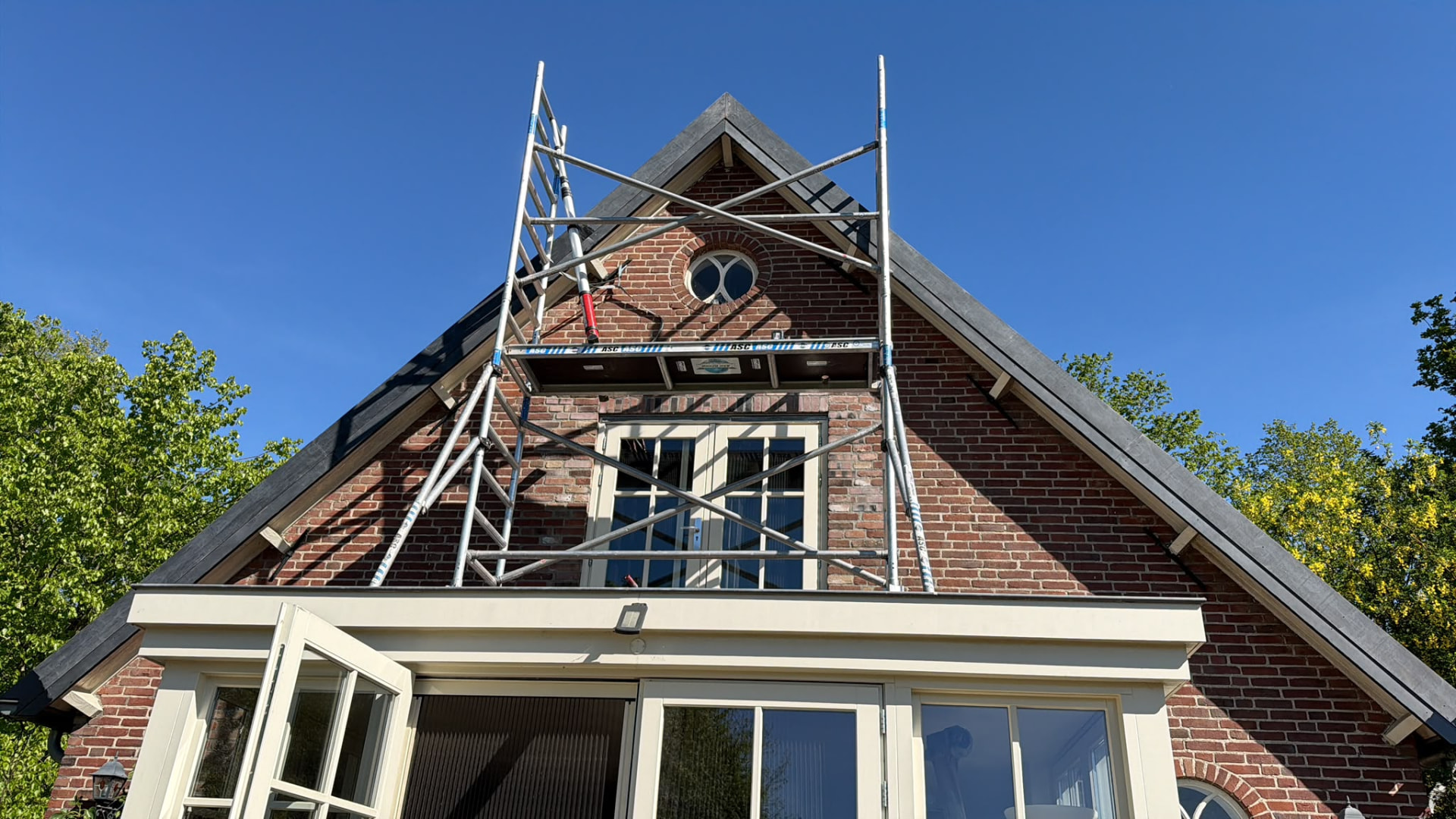 Bakstenen woning met afgewerkte donkere dakrand en nok